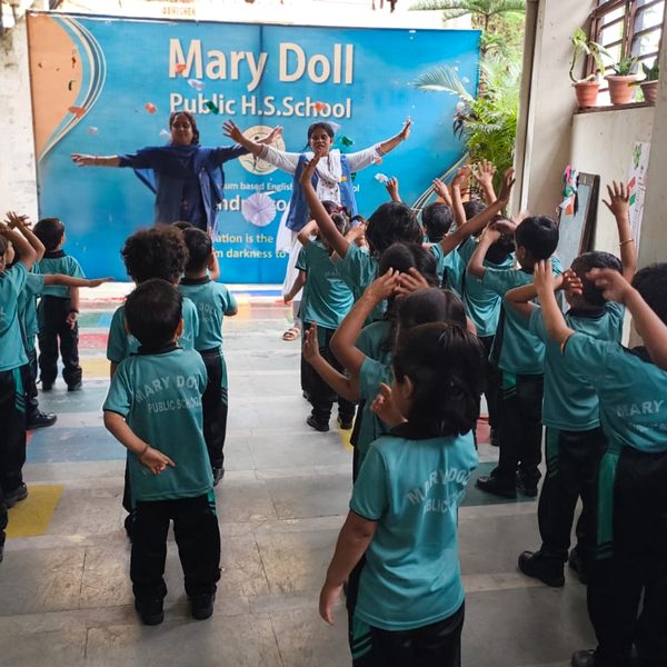 Students and a teacher doing morning exercises in front of the Mary Doll banner