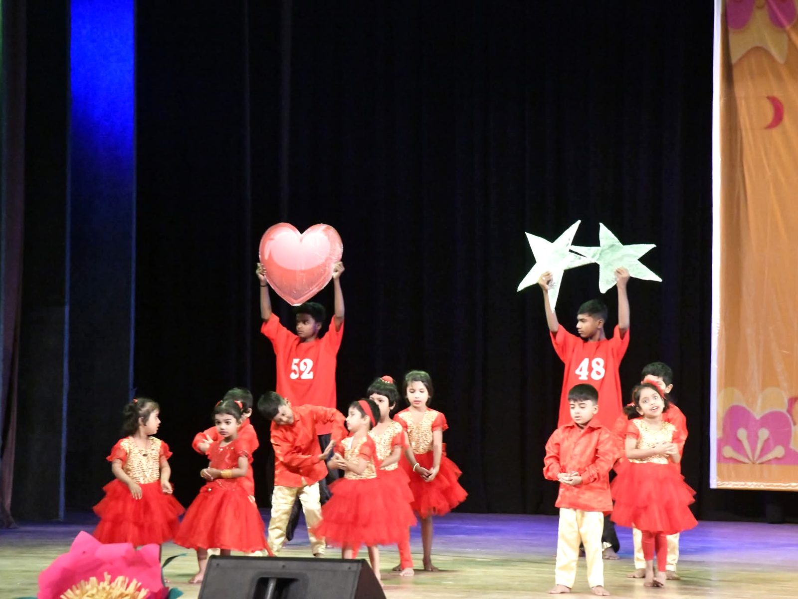 Young MDPS students performing on stage at the Annual Function, holding up a heart and stars