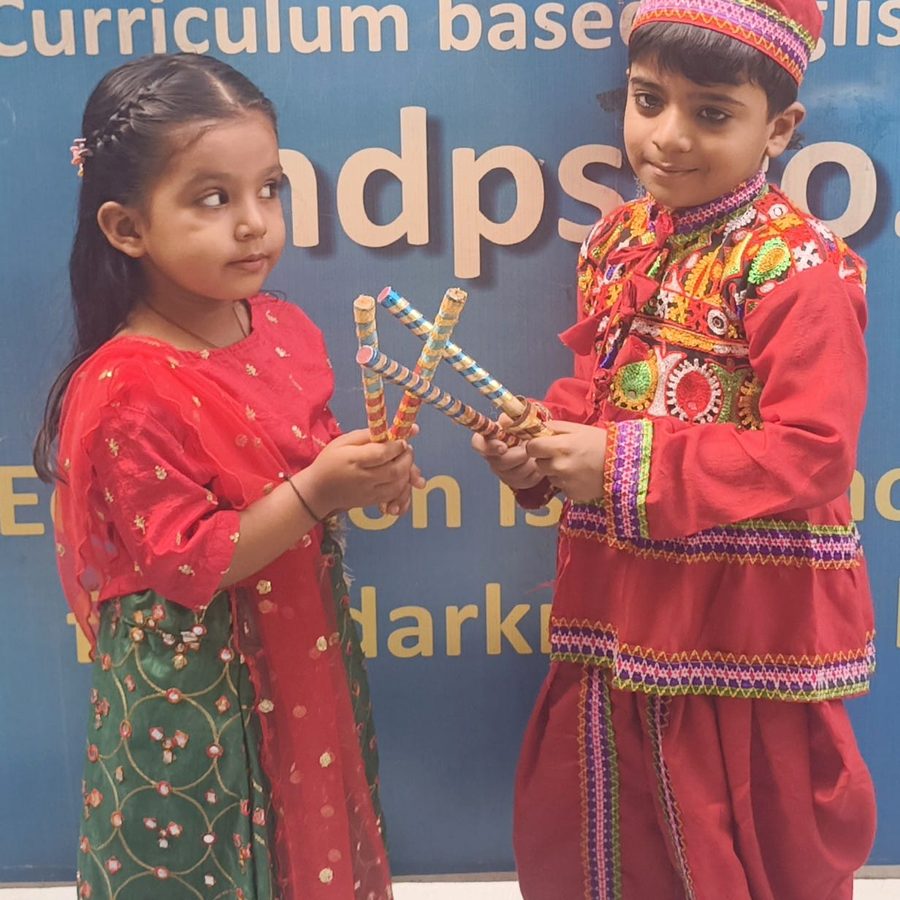Two students in Navratri dress holding dandiya sticks